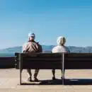 man and woman sitting on bench facing sea