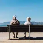 man and woman sitting on bench facing sea