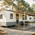 Mobil-home moderne blanc et gris dans un camping français entouré de pins, idéal pour un investissement locatif rentable
