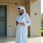 Musulman en thobe vérifiant l'heure de prière devant une mosquée moderne